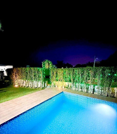Night view of illuminated pool and garden at Golden Venue farmhouse.