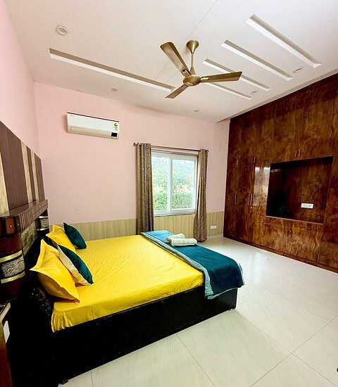 Elegant farmhouse bedroom with modern decor and large window at Golden Venue.