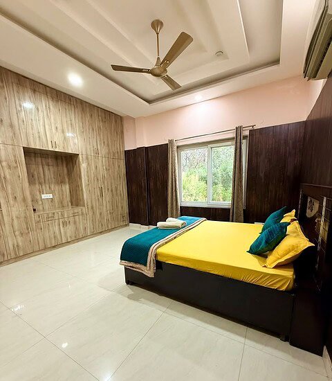 Spacious farmhouse bedroom featuring contemporary design, large window with scenic views, and comfor.