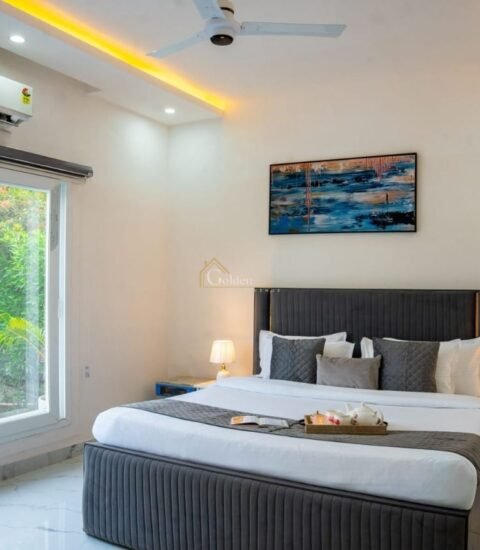 Farmhouse bedroom with a grey upholstered double bed, bedside tables, abstract painting and white wardrobe