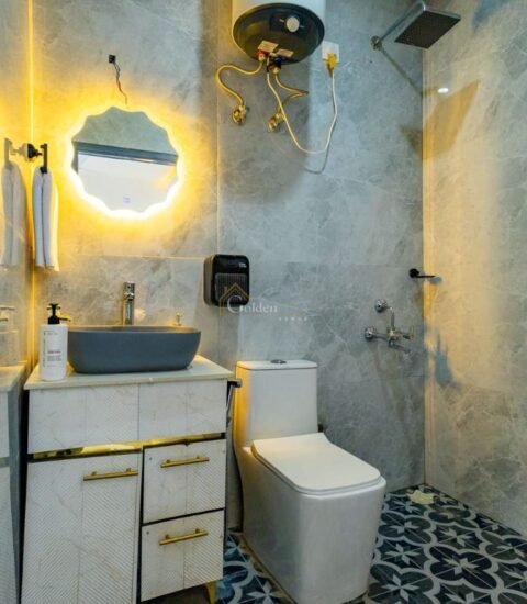 Bathroom with a round LED mirror, grey vessel basin, vanity cabinet and marble-look wall tiles