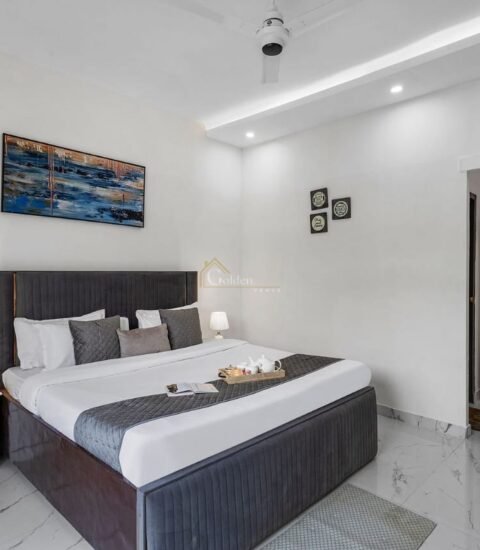 Farmhouse bedroom with a grey upholstered double bed, bedside tables, abstract painting and white wardrobe
