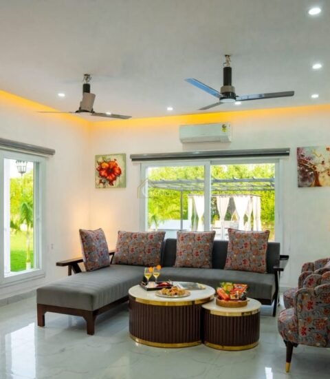Farmhouse living room with a grey sofa, two patterned armchairs, a wall AC and warm cove lighting