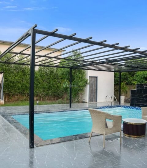 Private swimming pool under a black pergola with a curtained cabana and garden in the background