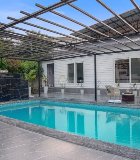 Rectangular pool with a black marble feature wall at the far end, pergola above and seating on the right