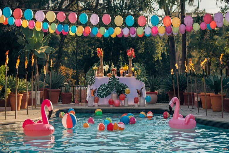 Vibrant poolside party with colorful decorations and floating flamingo inflatables at Golden Venue.
