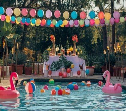 Vibrant poolside party with colorful decorations and floating flamingo inflatables at Golden Venue.